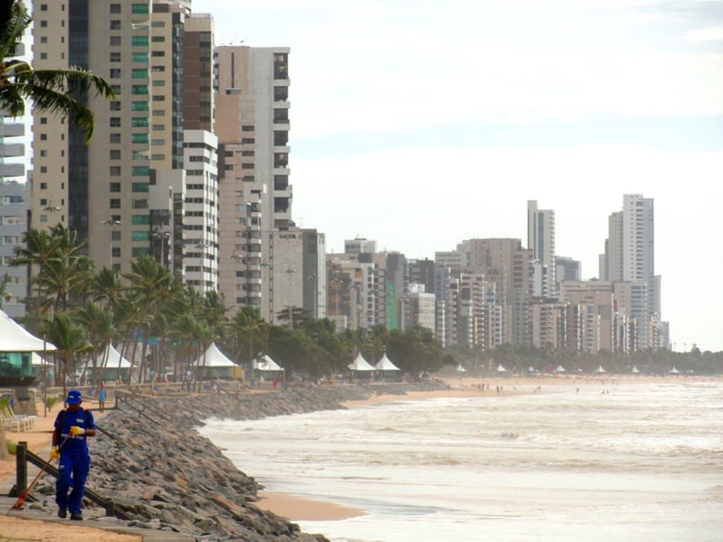 Orla de Boa Viagem, no Recife, com prédios altos, barracas na areia e o mar com ondas