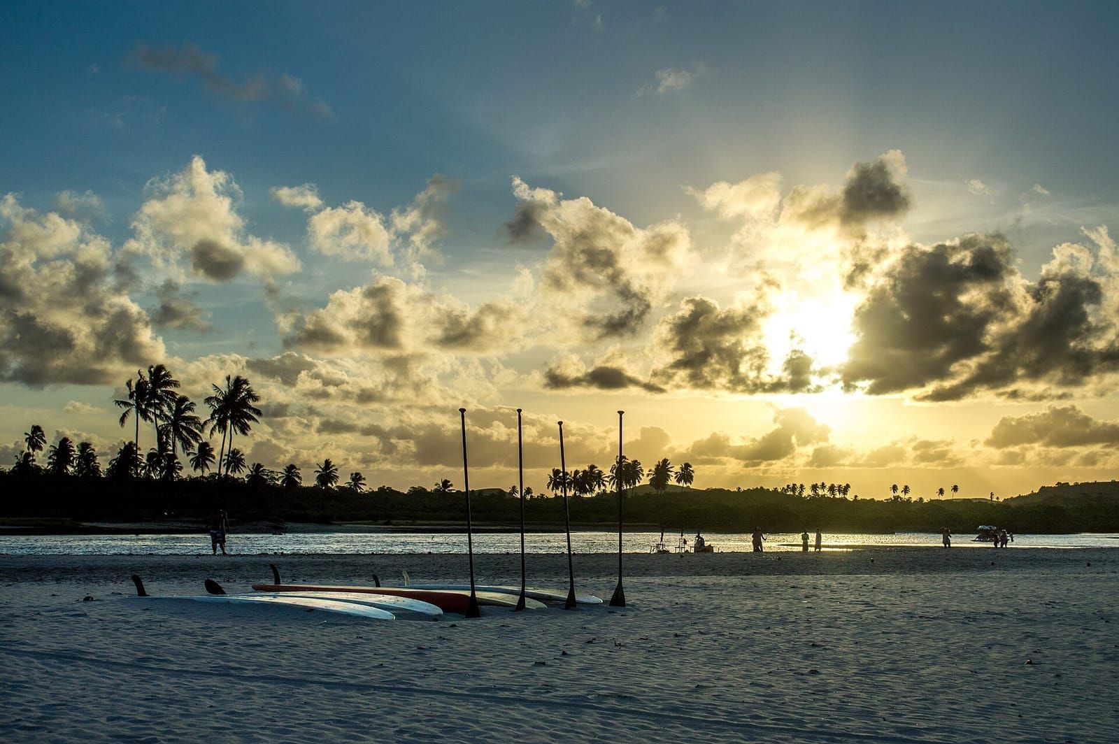 Pôr do sol no Pontal de Maracaípe, com coqueiros e barcos no estuário