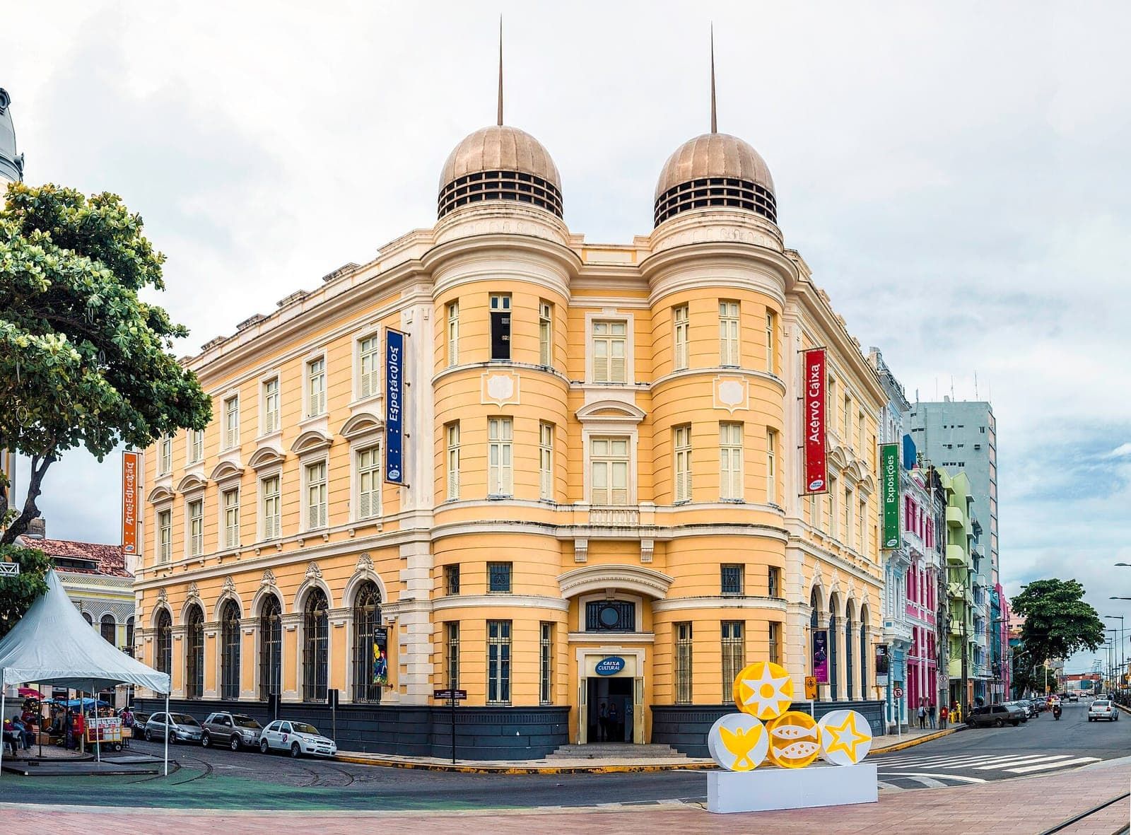 Prédio histórico amarelo com cúpulas diante da Praça do Marco Zero, no Recife Antigo
